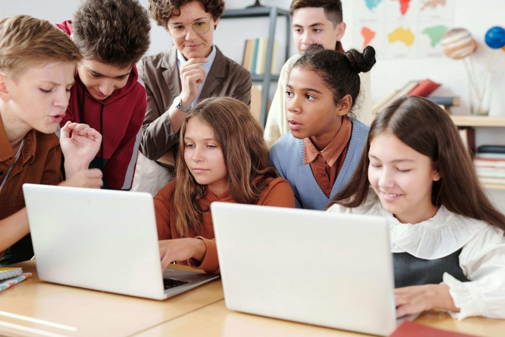 A group of diverse students working together on laptops in a classroom